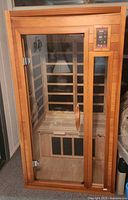 Full view of wooden indoor sauna with glass door and handle