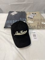 Overall lot view: two sealed T-shirts and black cap