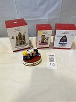 Three boxed Hallmark Keepsake ornaments and one loose piano scene ornament displayed