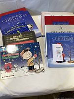 Assortment of eight Charlie Brown Christmas books on table showing covers and stacks