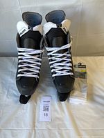 Front view of Bauer skates with laces, blade guards and packaged socks visible