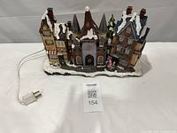 Front view of entire illuminated village piece with power cord