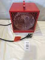 Front view showing red heater with mesh grille and corded plug