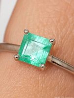 Close-up of square-cut Colombian emerald in four-prong 10K white gold setting