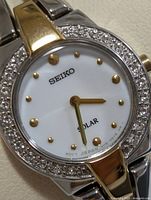 Front view showing crystal bezel, white dial, gold indices and hands