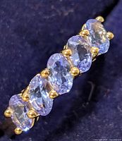 Close-up of ring showing five oval tanzanite stones and yellow-tone prongs