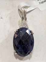 Front view of silver pendant with large dark blue oval gemstone