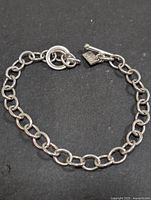 Full view of chain bracelet laid flat showing toggle clasp and tag
