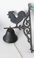 Side view showing entire cast iron bell, rooster finial, scroll bracket and bell