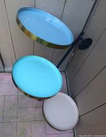 Front view showing three pastel round trays and black metal support