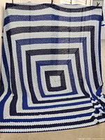 Full view of crocheted throw hanging to show size and color pattern