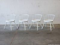 Front view of four matching white metal and wood dining chairs