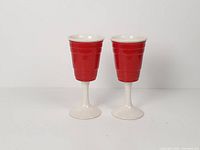 Front view of both ceramic red wine glasses with white stems
