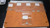 Five individual aquamarine gemstones in labeled plastic sleeves on a leatherette folder