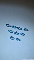 Nine faceted blue topaz stones arranged on neutral background