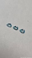 Three pear-cut blue zircons on neutral background
