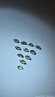 Group of 12 marquise green sapphires on flat surface