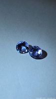 Pair of round violet-blue tanzanites on neutral background