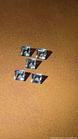 Five square aquamarine gemstones arranged on surface