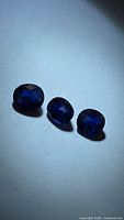 Trio of blue sapphire gemstones on white background under side lighting