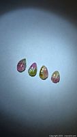 Four leaf-cut pink and green tourmaline stones on neutral background