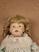 Close-up of doll’s face, blonde wig, lace collar