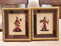 both framed embroideries side by side in gold wood frames