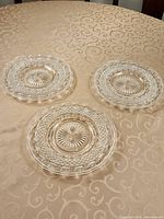 Three clear pressed glass plates on table
