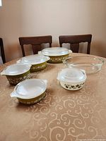 Six Pyrex casseroles with lids displayed on table showing pattern, colors, and shapes