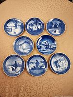 Eight Royal Copenhagen blue and white Christmas plates arranged on table showing front designs and years