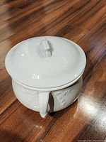 Lidded white chamber pot showing overall form and embossing