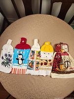 All five hanging kitchen towels laid flat showing designs and crochet tops