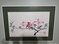 Front view showing entire framed painting with pink blossoms, green mat, white frame