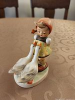 Full view of figurine showing girl, geese, colors, and base