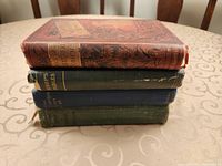 Stack of four hardcover books showing top book cover and spines