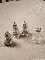 Four shakers arranged on patterned surface showing shapes and materials