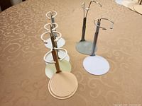 Six metal doll stands of two heights arranged on table