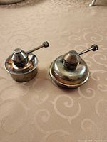 Both silver-plated oil burners side by side