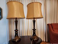 Front view of both bronze finish metal table lamps with beige fabric shades