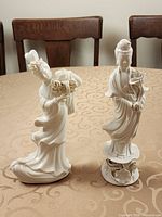 Both blanc de chine porcelain female figurines side by side on table