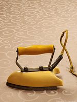 Front view of yellow travel iron showing handle, body, cord