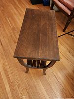Top view of brown wood side table showing grain, rectangular shape, slatted center, curved legs