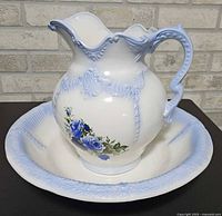 pitcher on basin showing overall design, blue scroll relief, floral decals