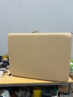 Folded cream massage table showing exterior and carry handle