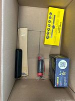 Overall contents of box from above showing yellow toy box, Impulse box, black hand pump, black case and two plain cartons