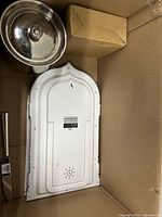 Overall box showing stainless pot lid, white plastic panel, knife handle, small box