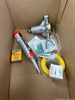 Overview of box showing water pump, sealant, capacitor box, anchors, masking tape, thermostat