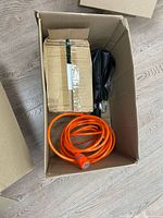 Top view of box showing orange cable, taped package, black umbrella