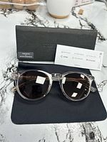 Sunglasses on cloth with case open showing branding card