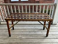 Full view of wooden slat laundry bench on porch